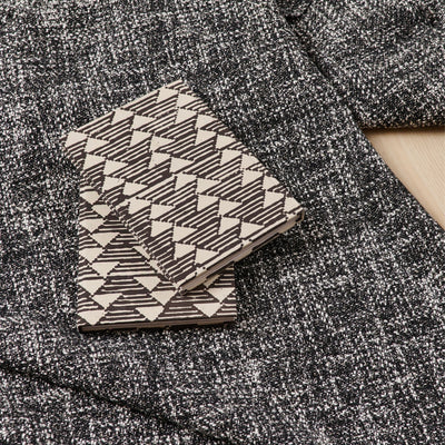 Tria Black White handmade journal resting on a textured charcoal-gray blanket