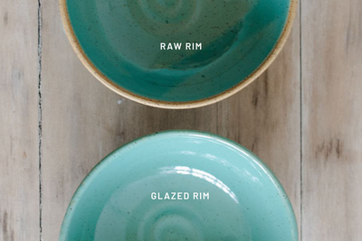 Two turquoise ceramic bowls with 'Raw Rim' and 'Glazed Rim' labels on a wooden surface, by KJ Pottery