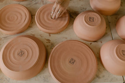 Underside of handmade earthenware plates showing maker stamp KJ Pottery