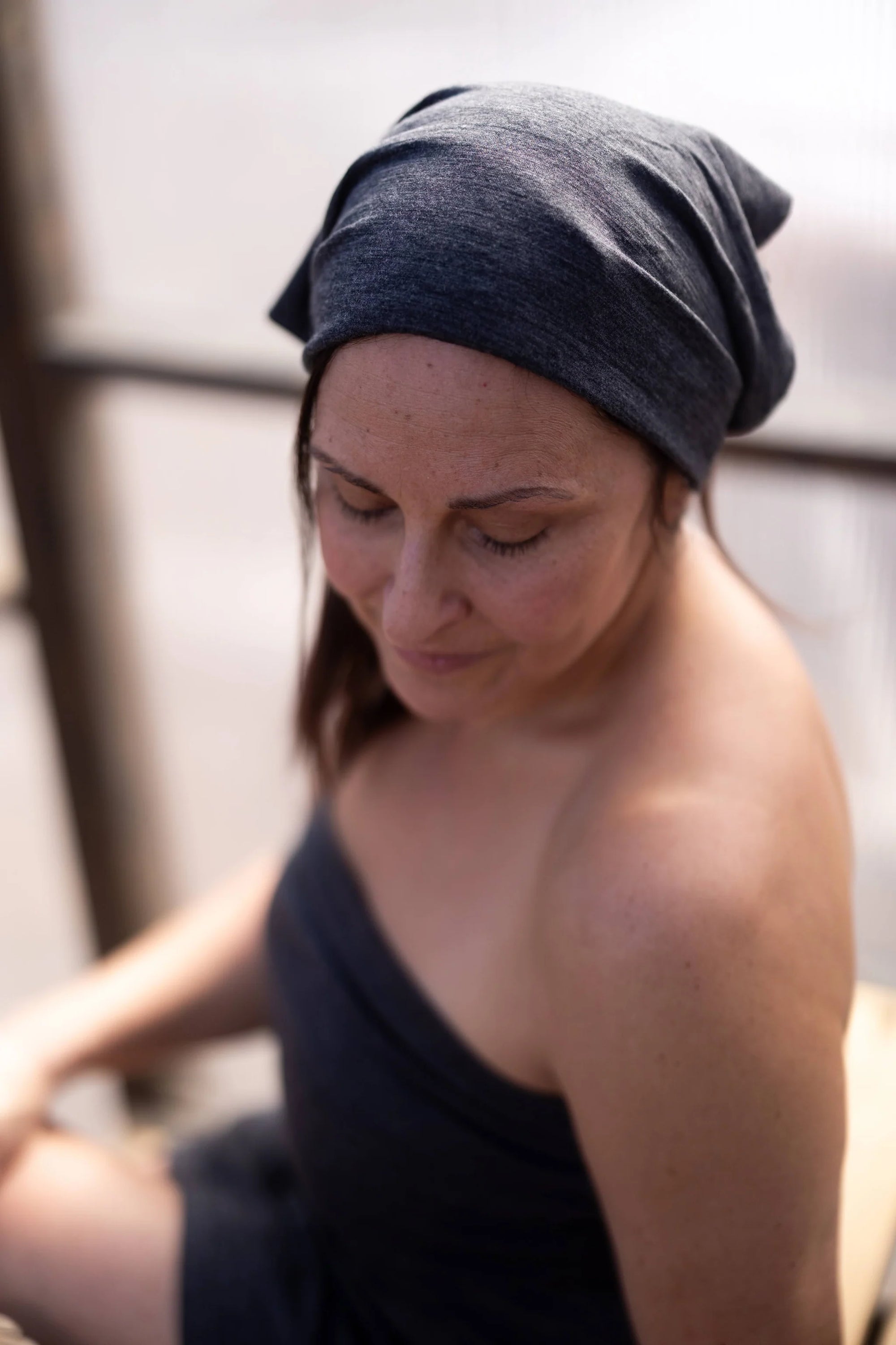 Woman wearing a charcoal merino wool bandana designed for heat, cold plunge, recovery, and daily comfort.