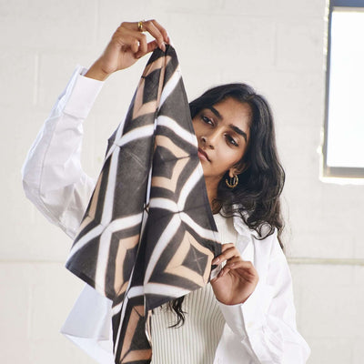 Woman holding up one corner of the lightweight patterned cotton napkin.