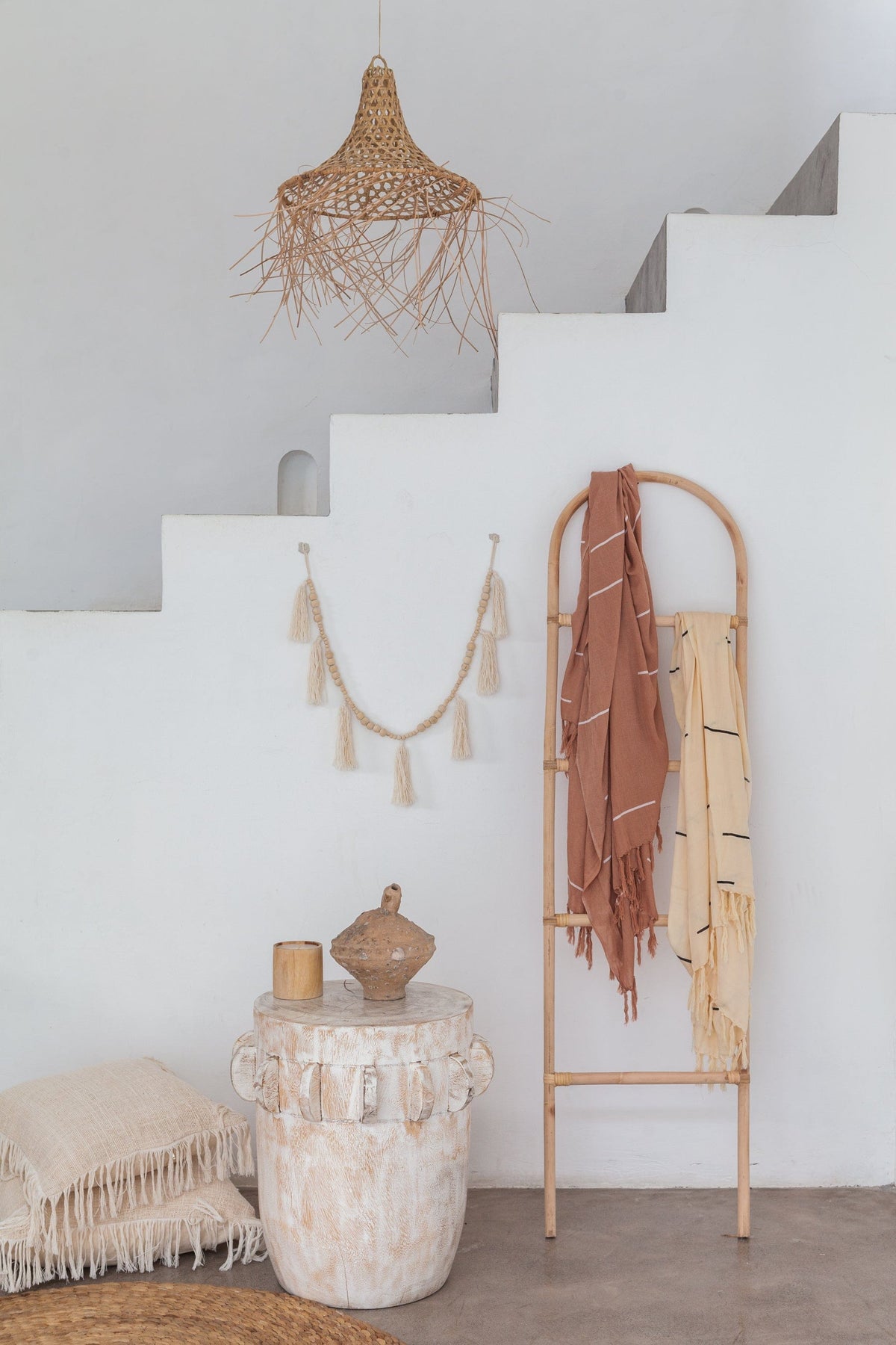 Village Thrive Lines Tapestry, taupe rayon, draped over a wooden ladder beside a hanging rattan pendant and stairway.