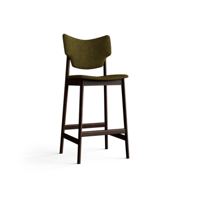 Three-quarter front view of the olive-green Eikund Veng Bar Stool, showing the curved backrest, projecting seat edge, splayed wood legs, and connecting footrest rails.