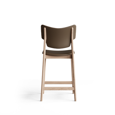 Rear view of the Eikund Veng Counter Stool with smooth taupe-brown upholstery and a light wood frame, showing a curved backrest with raised corners, exposed back supports, tapered legs, and horizontal crossbars.