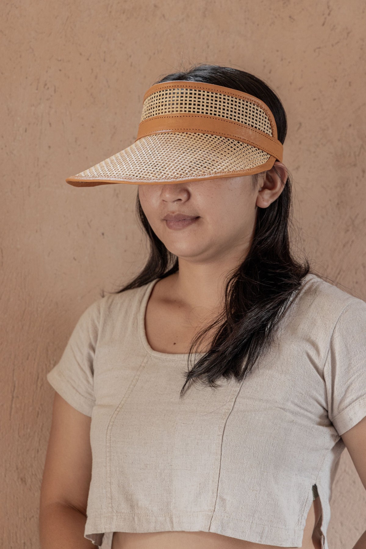 Village Thrive Sumi Leather and Cane Rattan Visor, camel rattan cane with dark leather trim, worn facing forward.
