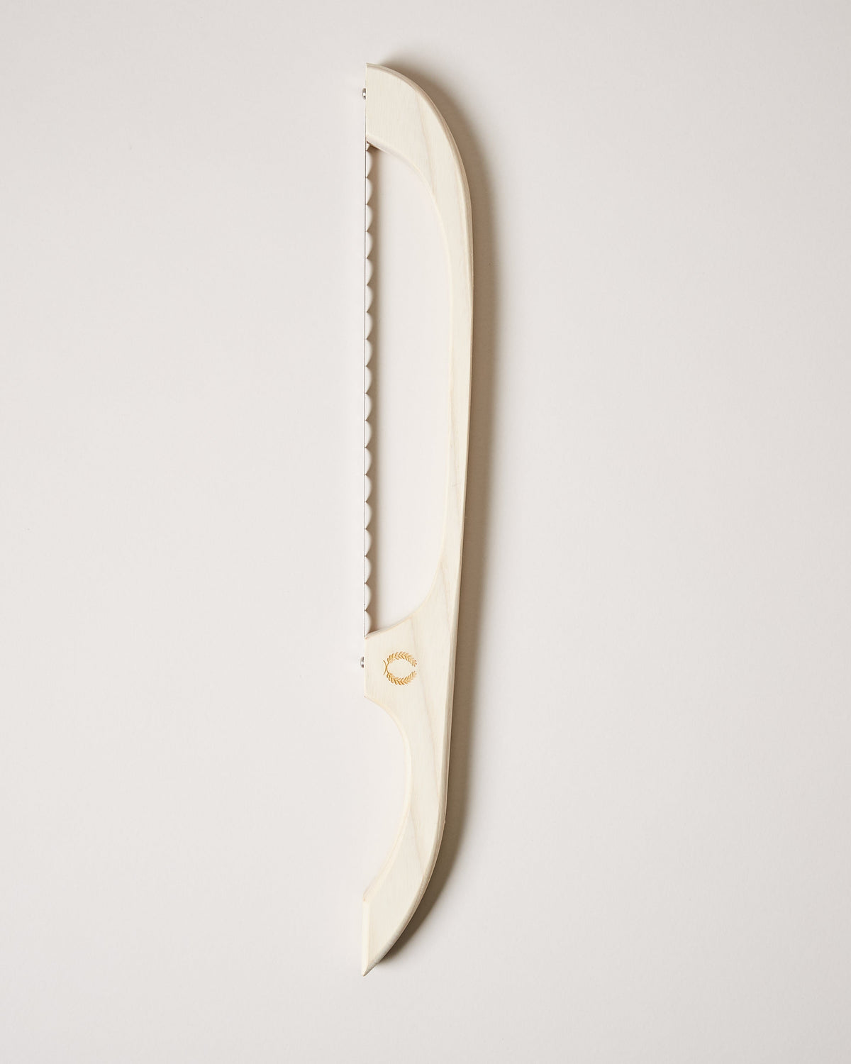 Cream-colored bread bow with a serrated metal blade and gently curved frame displayed against a pale background.