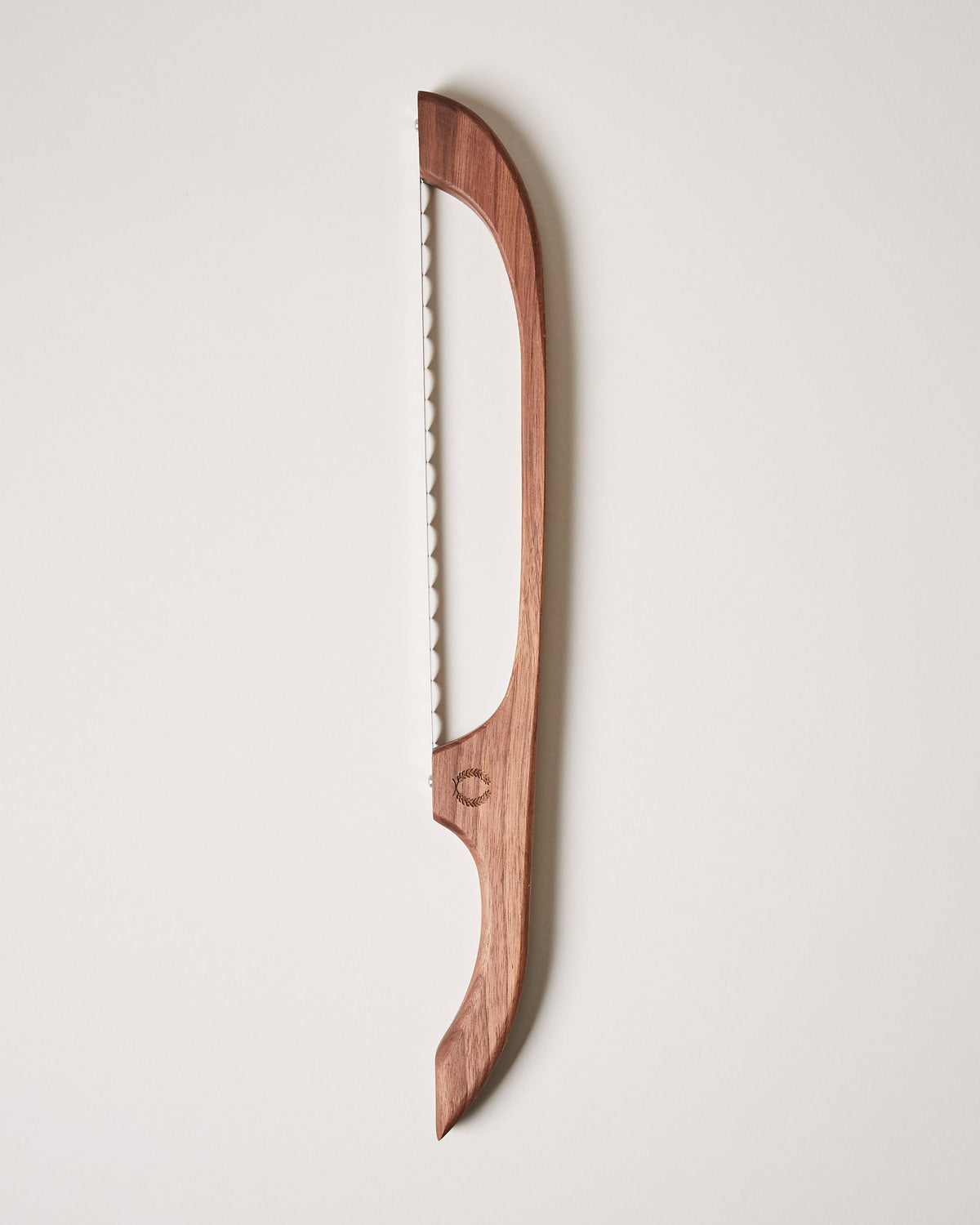 Dark reddish-brown wooden bread bow with a long serrated blade stretched along the inside of its curved frame.