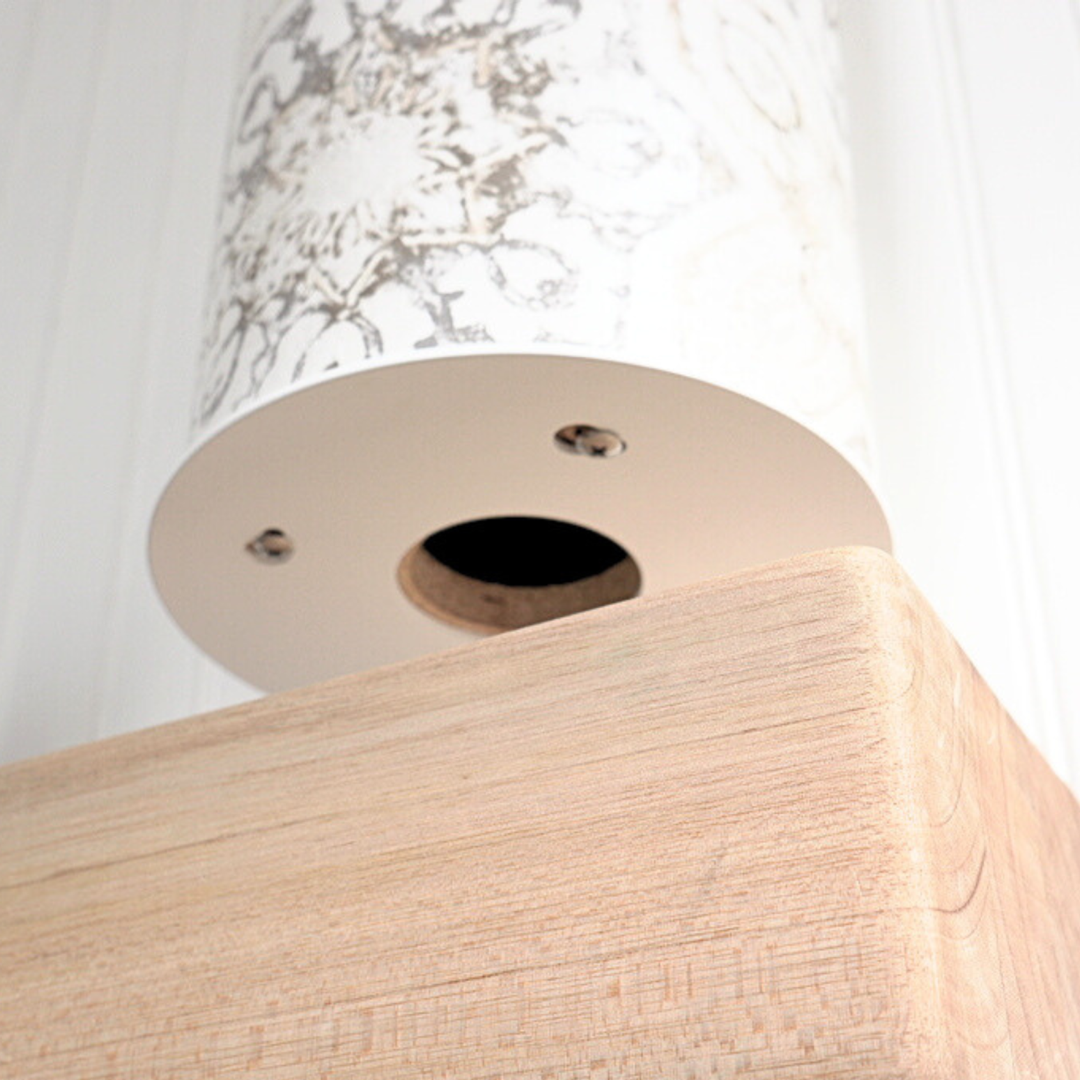 Low-angle detail of the pale wood base’s underside, showing a circular opening and metal fasteners.