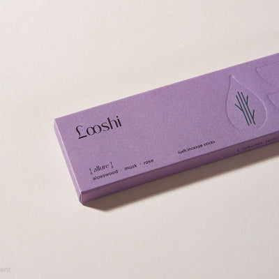 Lavender box of Looshi Allure incense sticks on a cream surface, featuring aloeswood, musk and rose fragrances