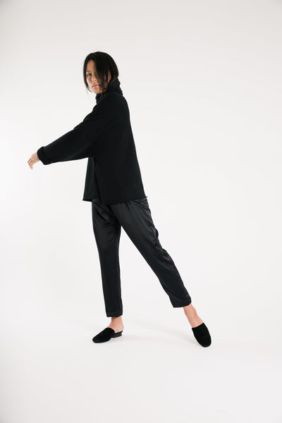 Side view of model stepping forward in black Souk pants and a matching top.