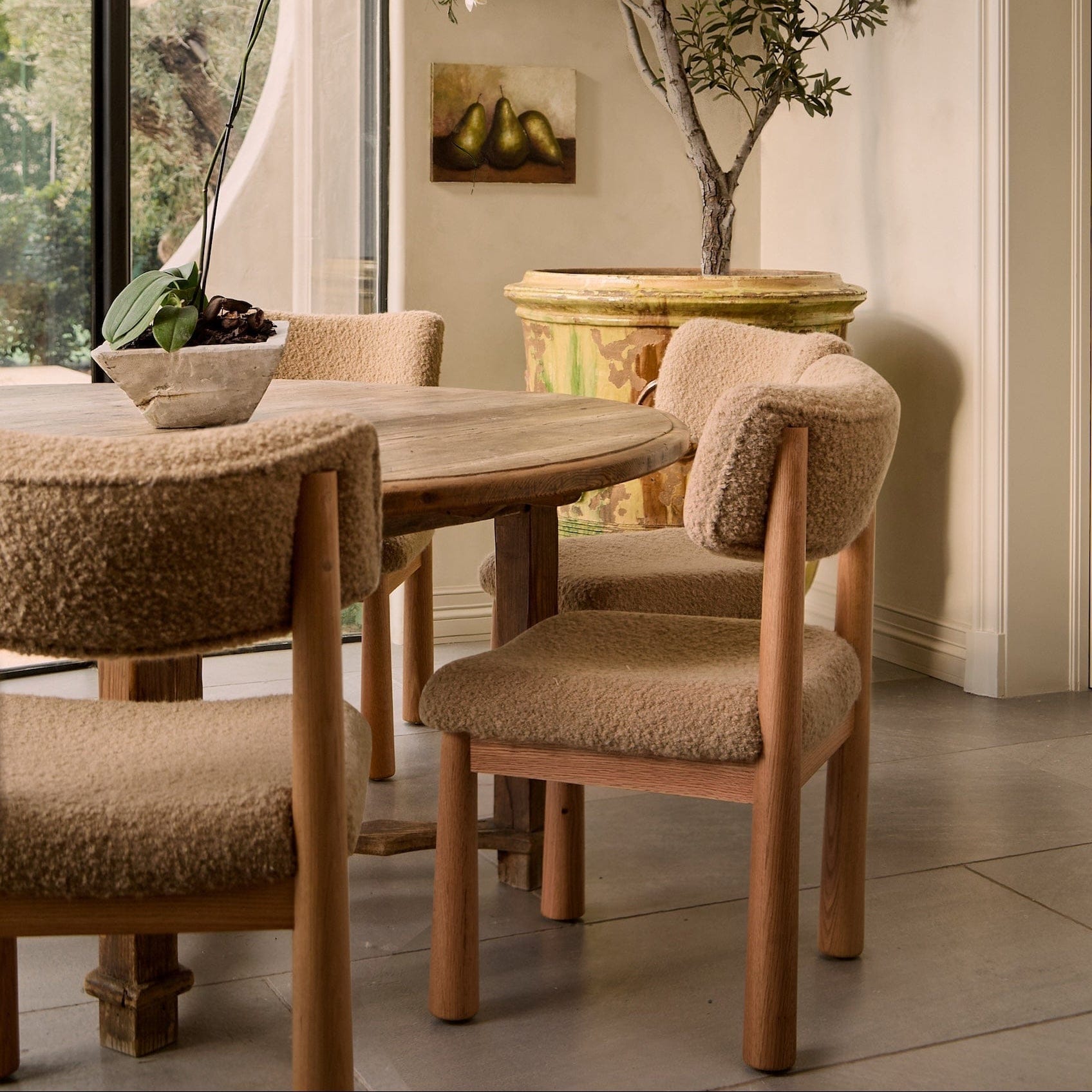 Dining room with wooden table and chairs with textured beige cushions.