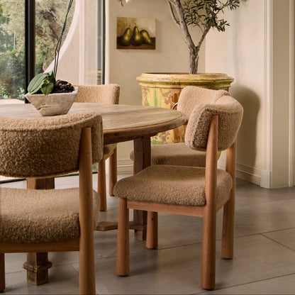 Dining room with wooden table and chairs with textured beige cushions.
