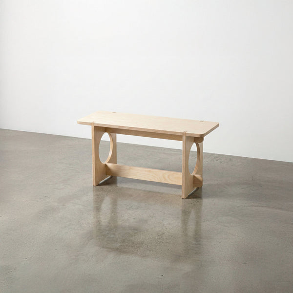 Studio Furnis YOYO natural wood bench with a rectangular seat, rounded corners, circular side openings and a low support rail on a polished concrete floor