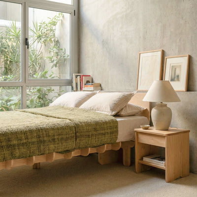 Angled view of the DOVID bed frame with olive green bedding beside a wood nightstand and large window