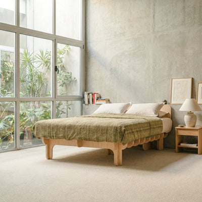 DOVID natural wood bed frame with textured olive green bedding in a modern concrete bedroom with floor-to-ceiling windows