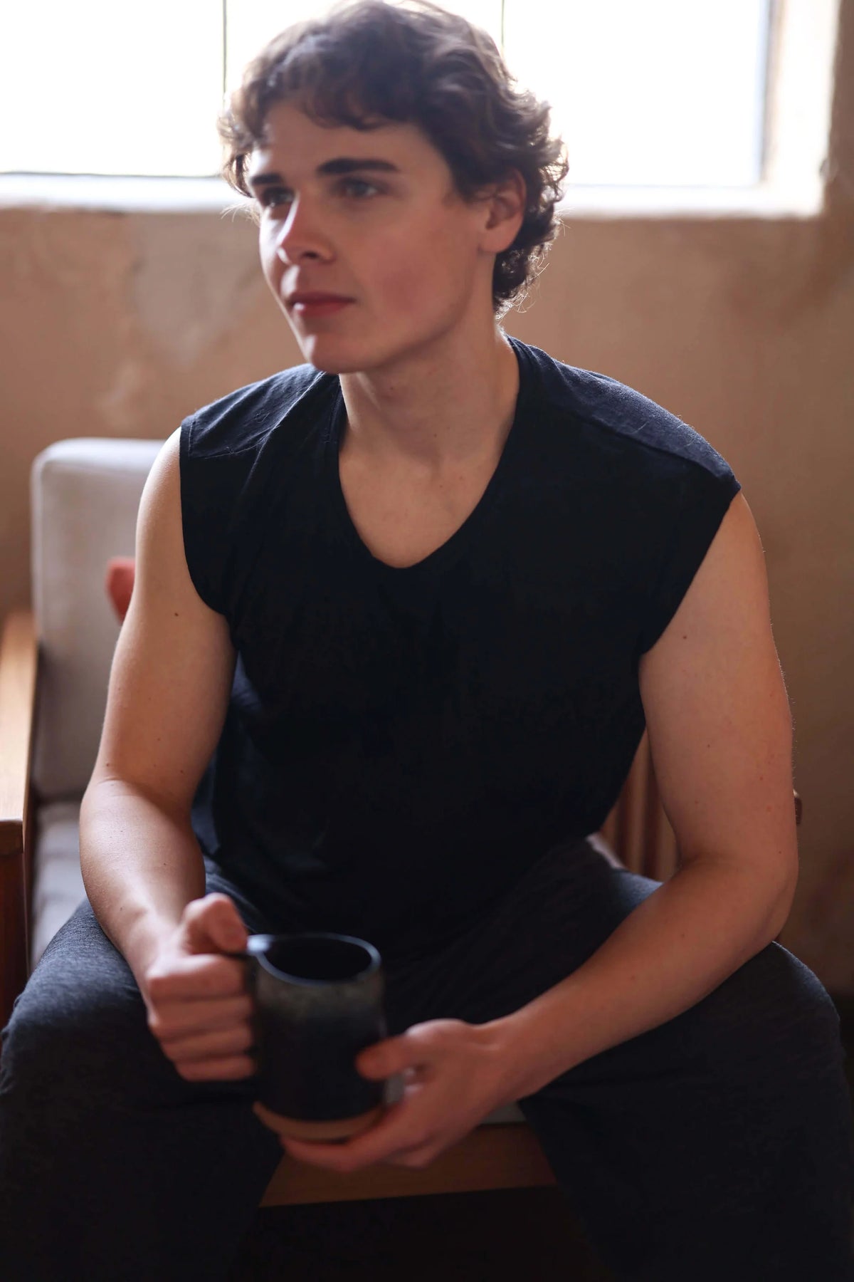 Man relaxing in a charcoal merino wool sauna tee, highlighting lightweight comfort and natural temperature regulation.