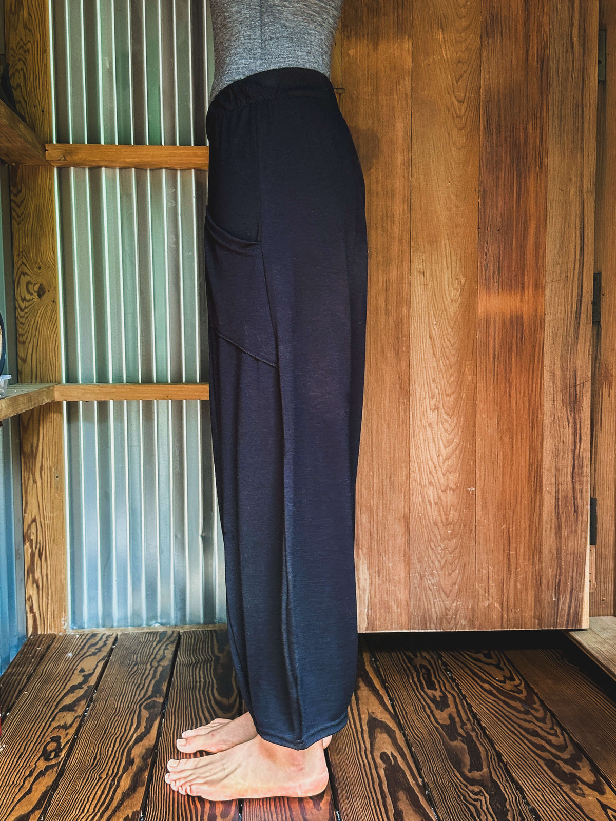 Side view of black merino wool lounge pants featuring a slightly longer silhouette and comfortable drape.