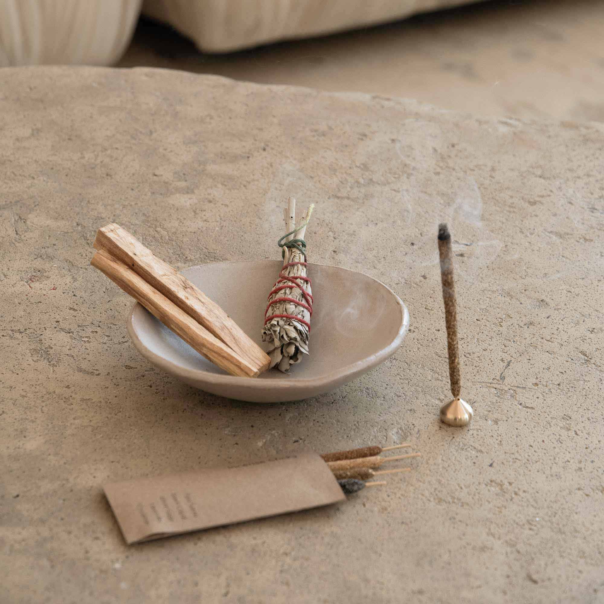 Incense sticks and a small dish on a stone surface