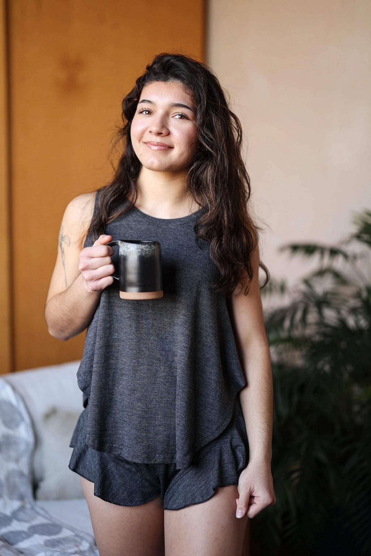 Woman wearing a merino wool sauna cami while enjoying a quiet morning, showcasing breathable comfort and natural drape.