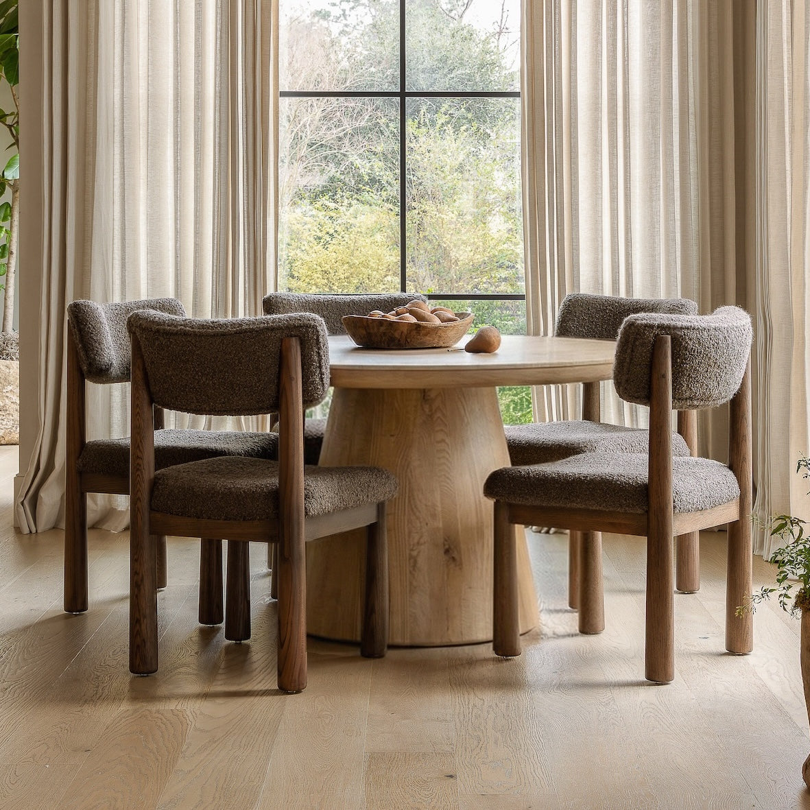 Dining room with wooden table and chairs near large windows by House of Leon.