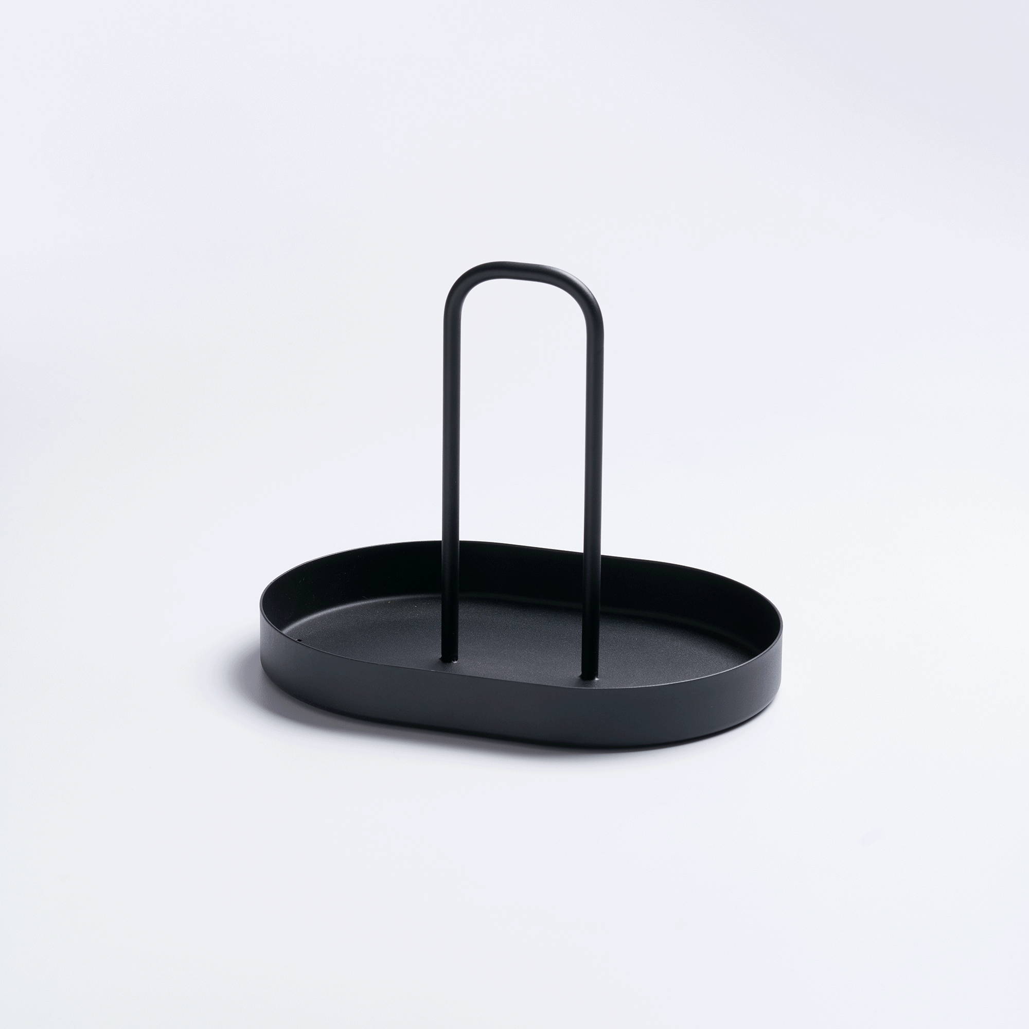 Empty black Yamazaki Home Vanity Tray with Handle - Steel on a pale background, viewed from above at an angle to show its oval base, raised edge and upright loop handle.