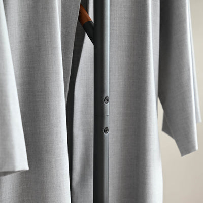 Close-up of the black Yamazaki Home Coat Rack (70" H) - Steel pole joint and two screw heads visible between the folds of a hanging grey coat.