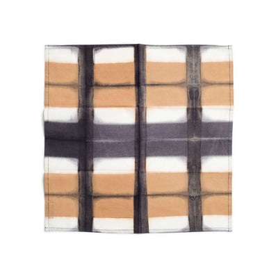 Single Chowk Black table napkin laid flat to display its bold hand-dyed black grid over tan and white blocks