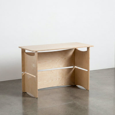 Front view of the Williamsburg natural wood desk showing its wide modesty panel, open supports and elevated desktop shelf