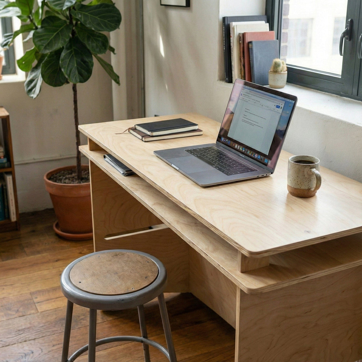 Elevated view of the Williamsburg desk with an open laptop and mug, highlighting the layered desktop and pale natural wood grain