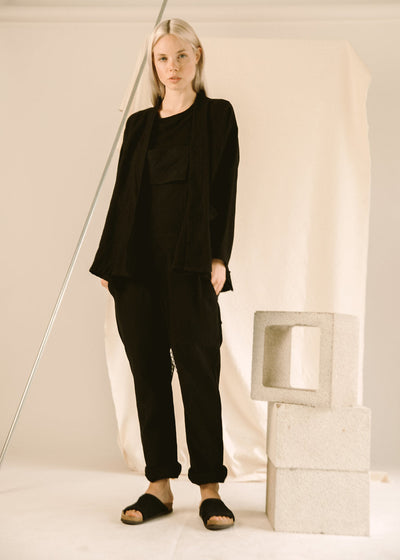 Model wearing a black GI jacket with matching black pants and sandals.