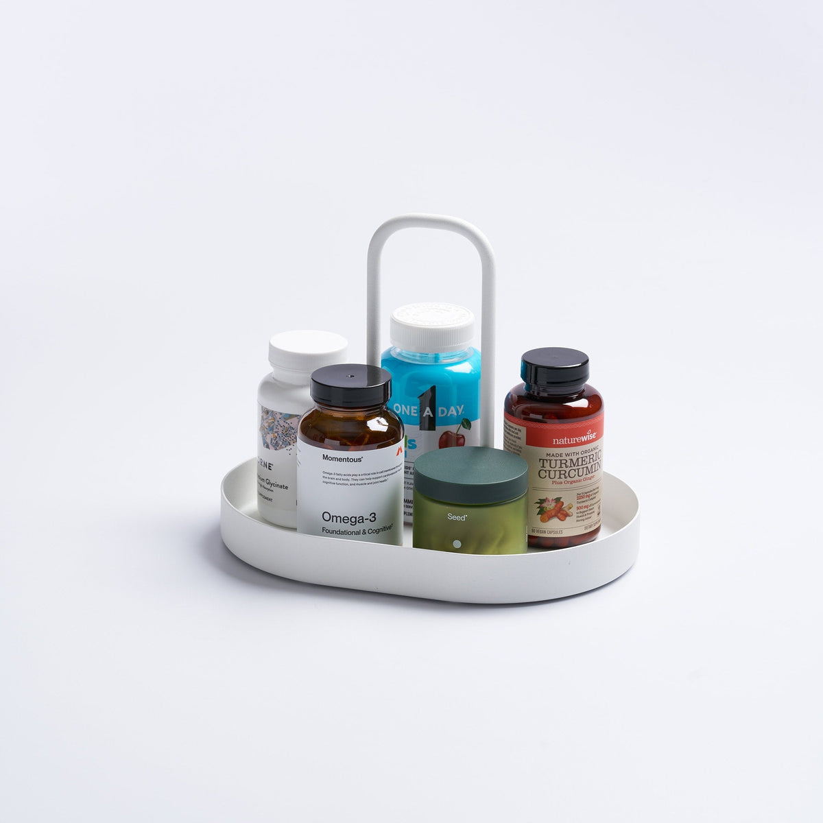 White Yamazaki Home Vanity Tray with Handle - Steel holding assorted supplement bottles and a green jar, with a shallow oval base, raised rim and tall rounded rectangular handle.