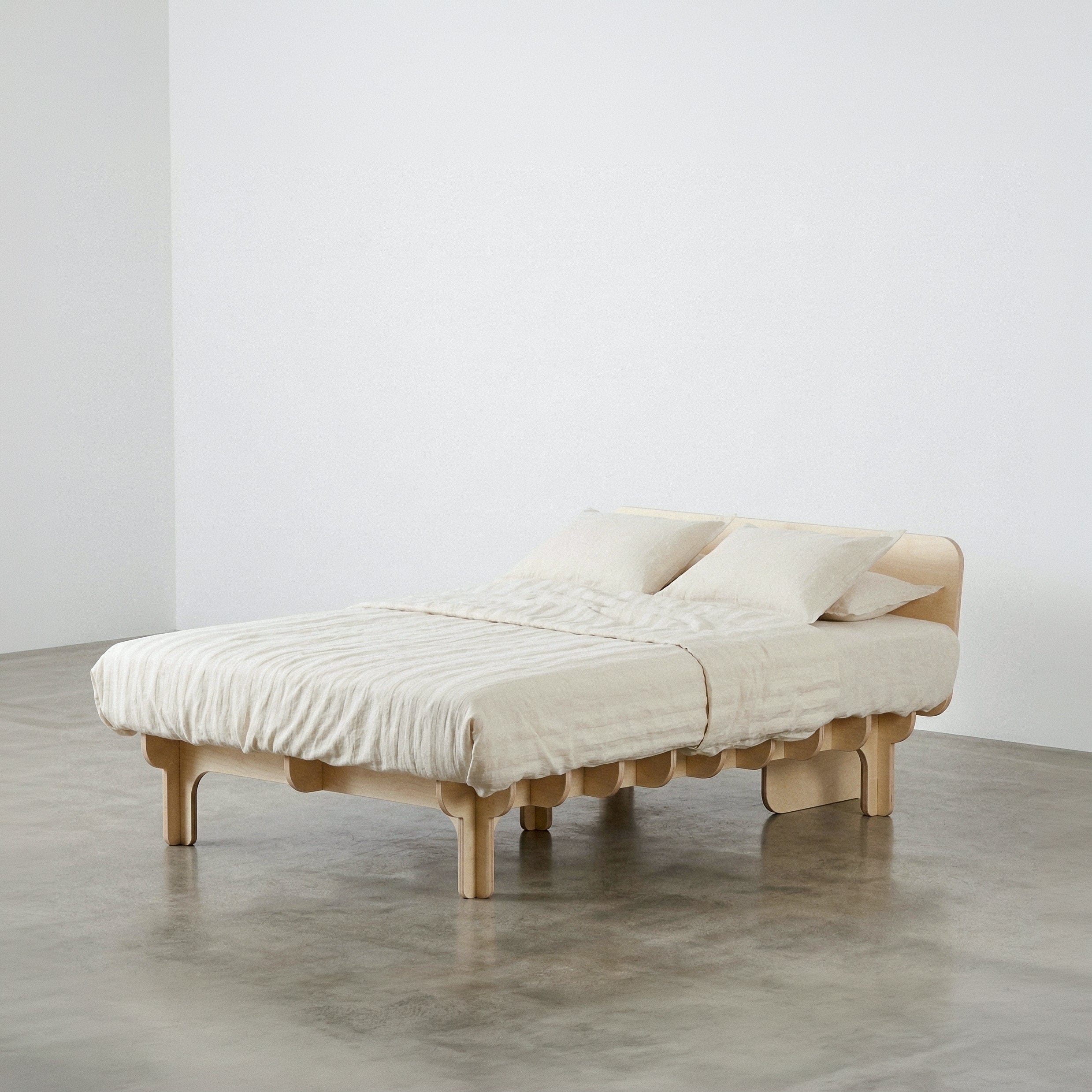 Medium-width DOVID wood bed frame with white bedding, shown from the front-left to display its platform and support legs
