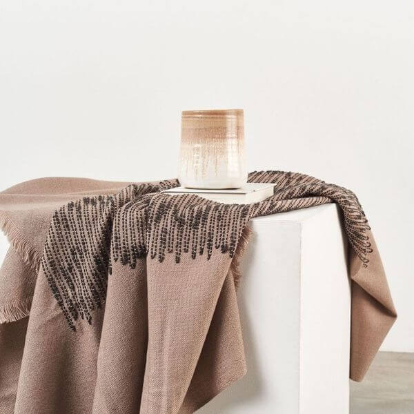 Flo Brown handloom throw draped across a white pedestal table and styled with a neutral candle