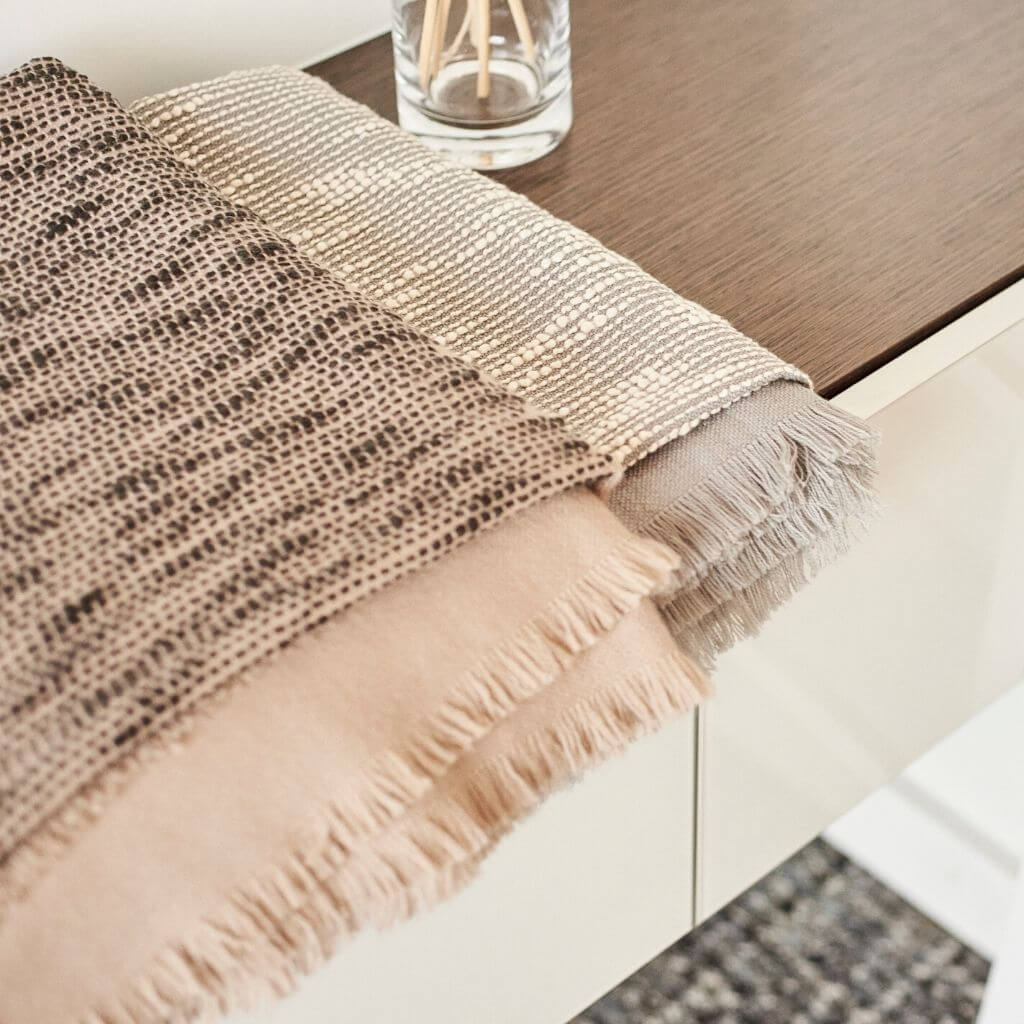 Close-up of the folded Flo Brown throw showing its dark woven detailing, taupe base and soft fringe