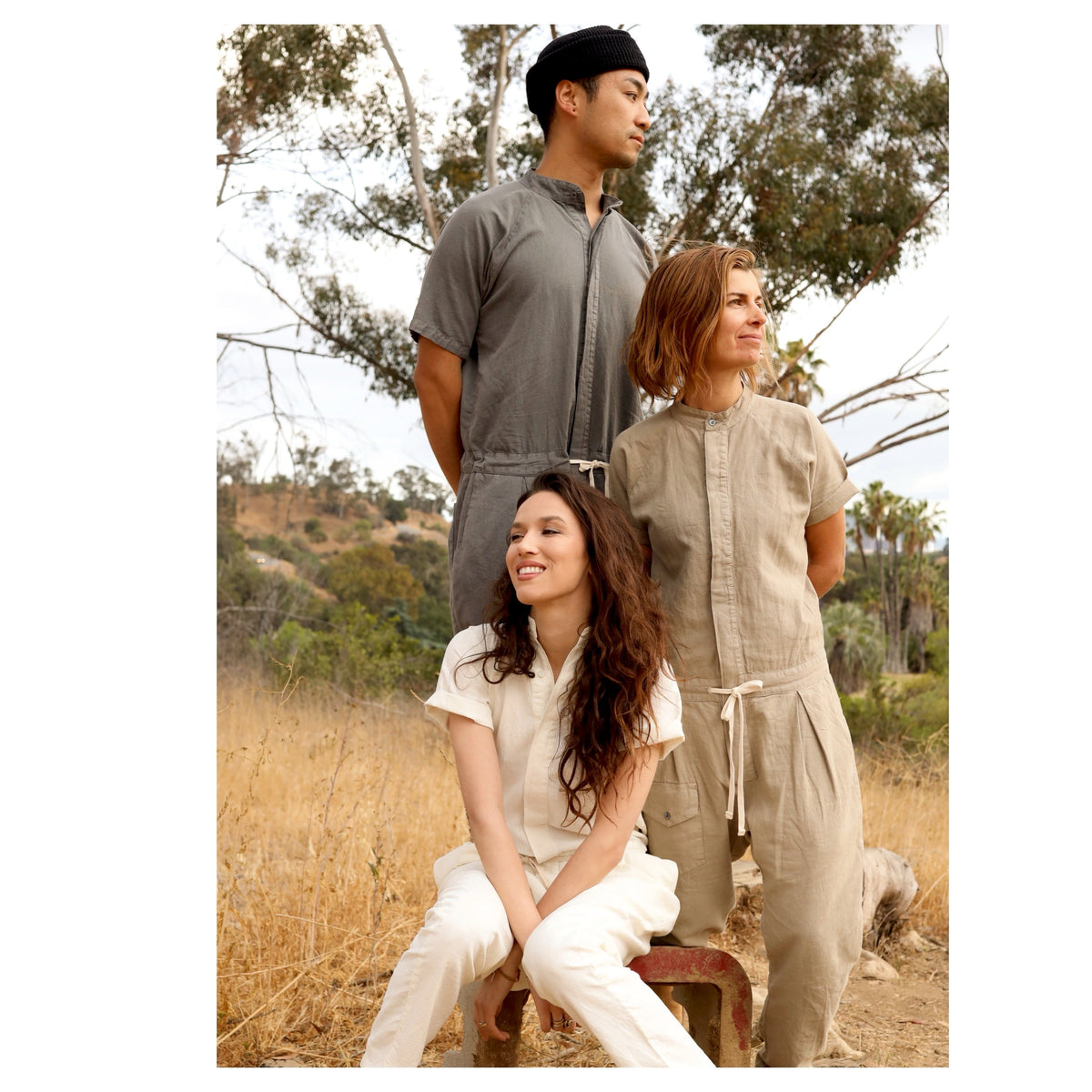 Three models wearing gray, tan, and white short-sleeve jumpsuits outdoors.