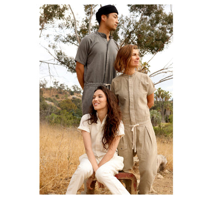 Three models wearing gray, tan, and white short-sleeve jumpsuits outdoors.