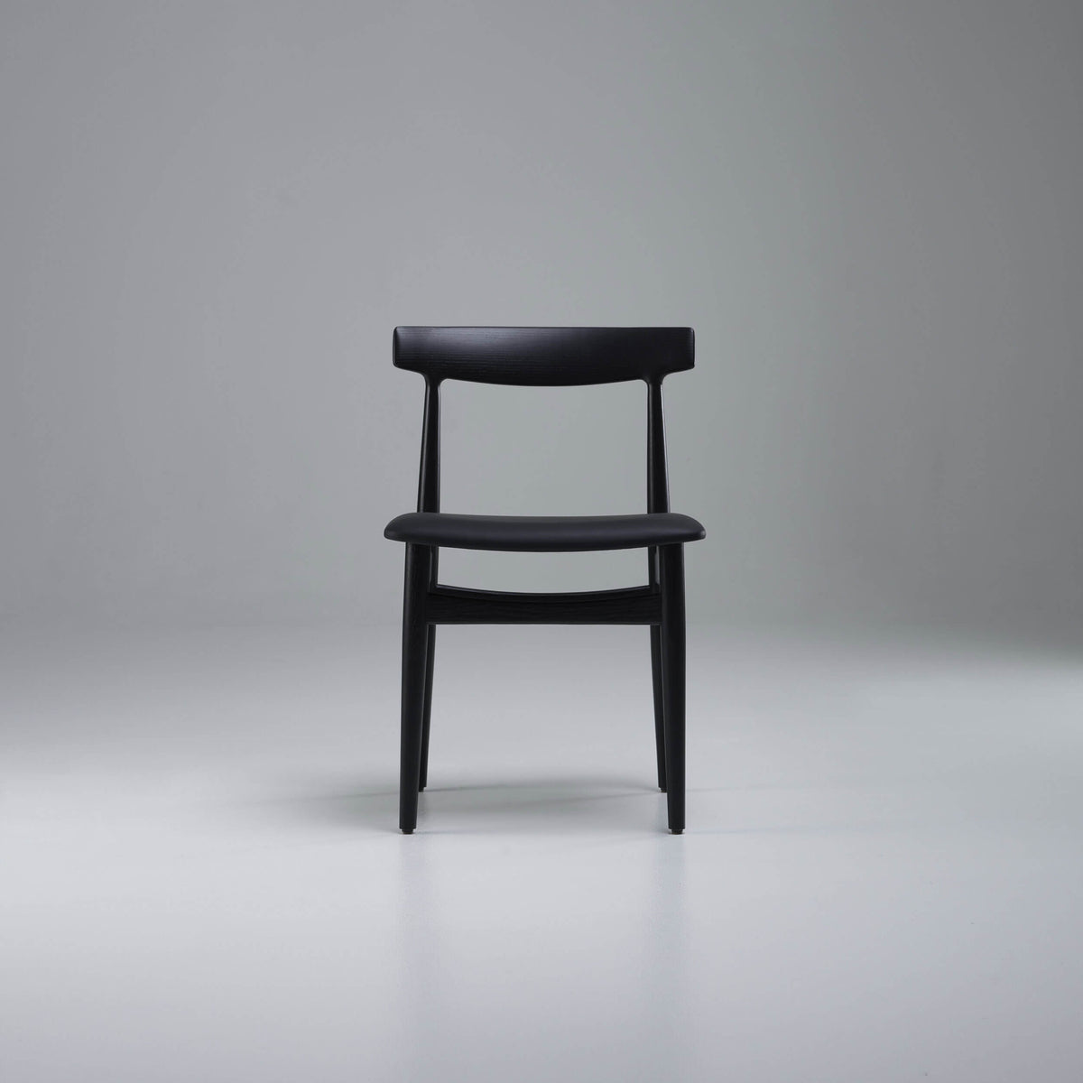 Front view of the black Eikund Hertug Dining Chair, showing the narrow curved backrest, open back, and slender legs against a gray studio background.