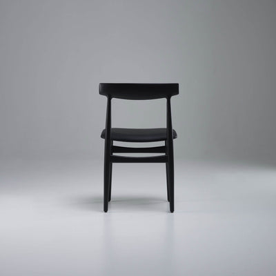 Rear view of the black Eikund Hertug Dining Chair, showing two slim back uprights and curved horizontal rails beneath the seat.