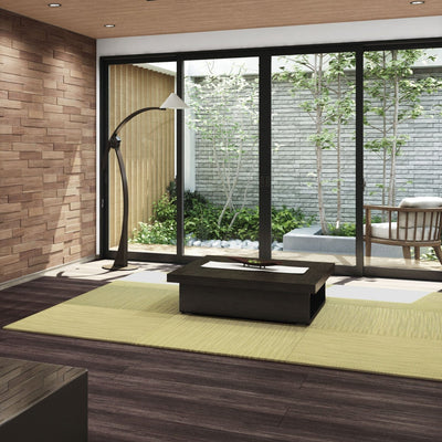 A modern room featuring Japandi Tatami Mats in an alternating pattern in a silver-green color, laid out on the floor with a Japanese-style room in the background, including a low wooden table and a floor lamp.