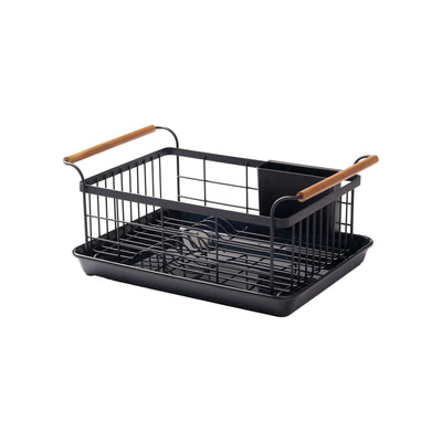 Empty black Yamazaki Home Dish Rack - Steel + Wood isolated on white, showing its open wire basket, curved plate slots, divided utensil caddy, two wooden handles and rectangular drip tray.