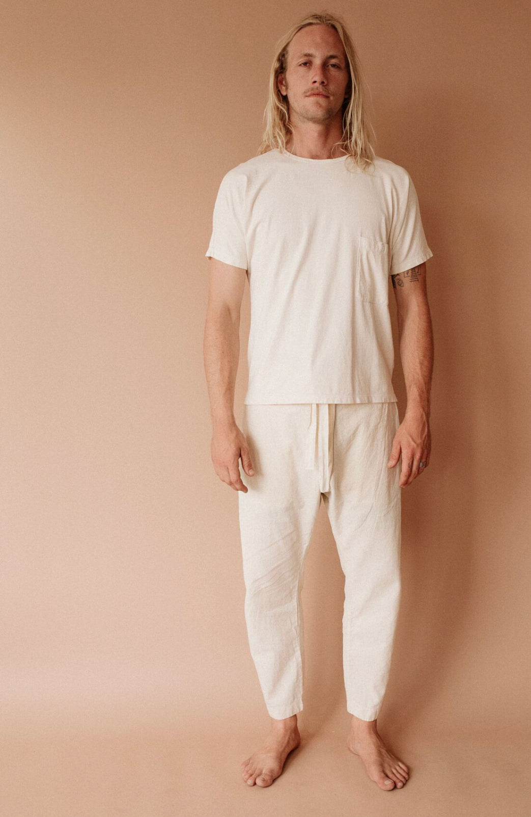 Barefoot model wearing natural cream Canvas Souk pants with a matching cream T-shirt.