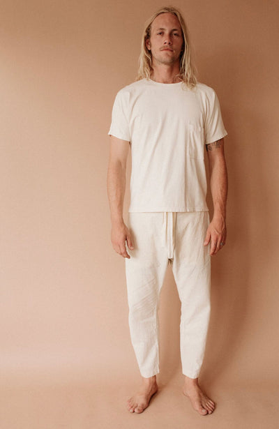 Barefoot model wearing natural cream Canvas Souk pants with a matching cream T-shirt.