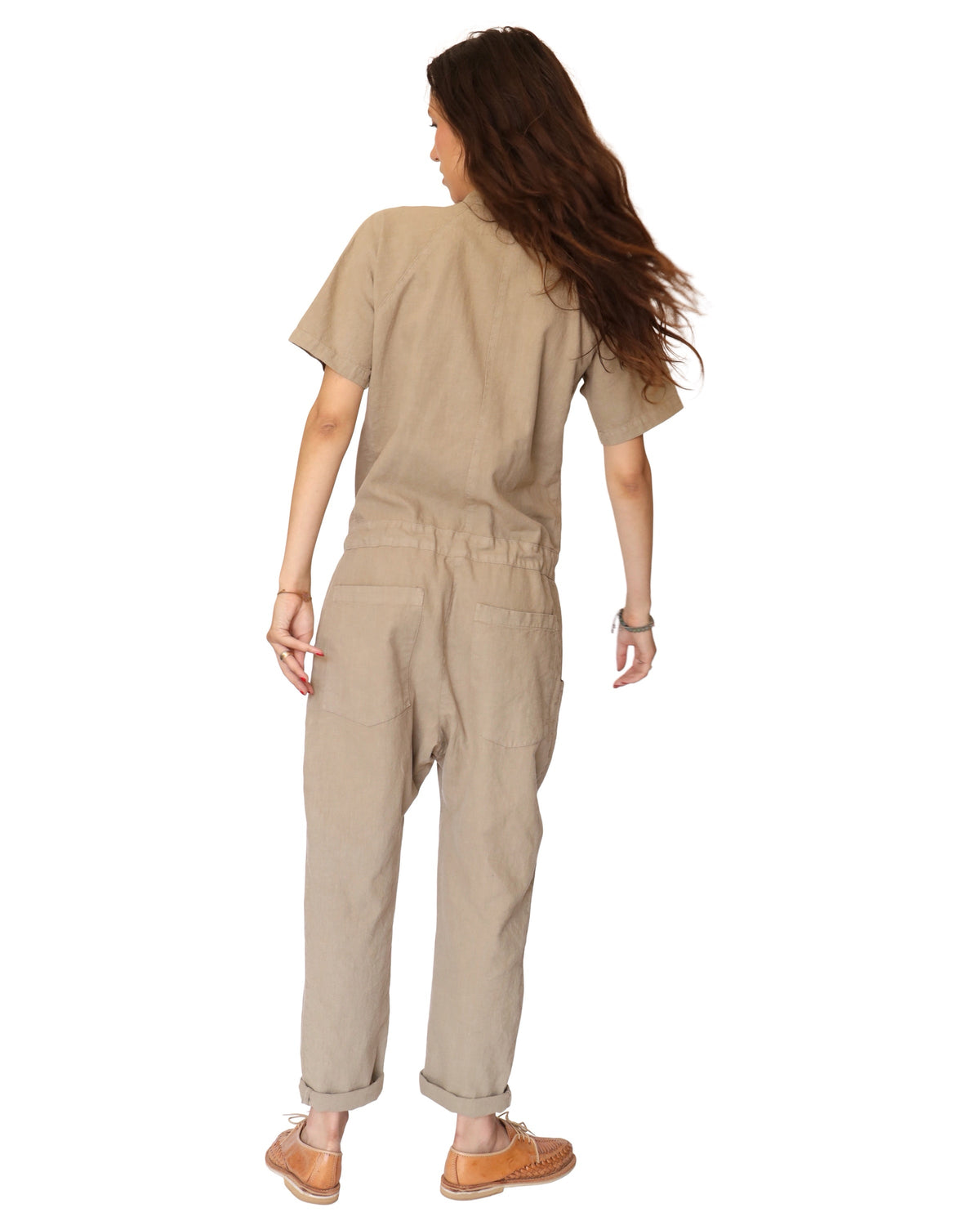 Rear view of a model wearing the tan short-sleeve jumpsuit.