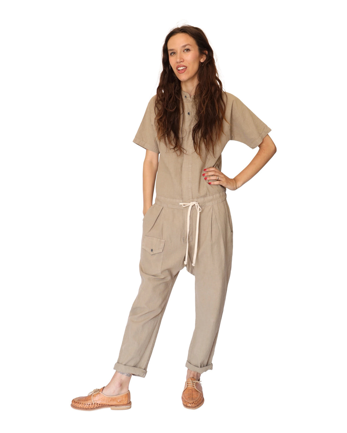 Front view of a model wearing the tan short-sleeve jumpsuit with rolled cuffs.