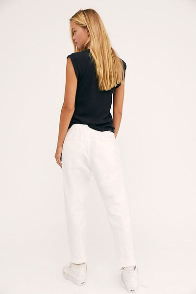 Back view of a model wearing white Canvas Souk pants with a black sleeveless top.