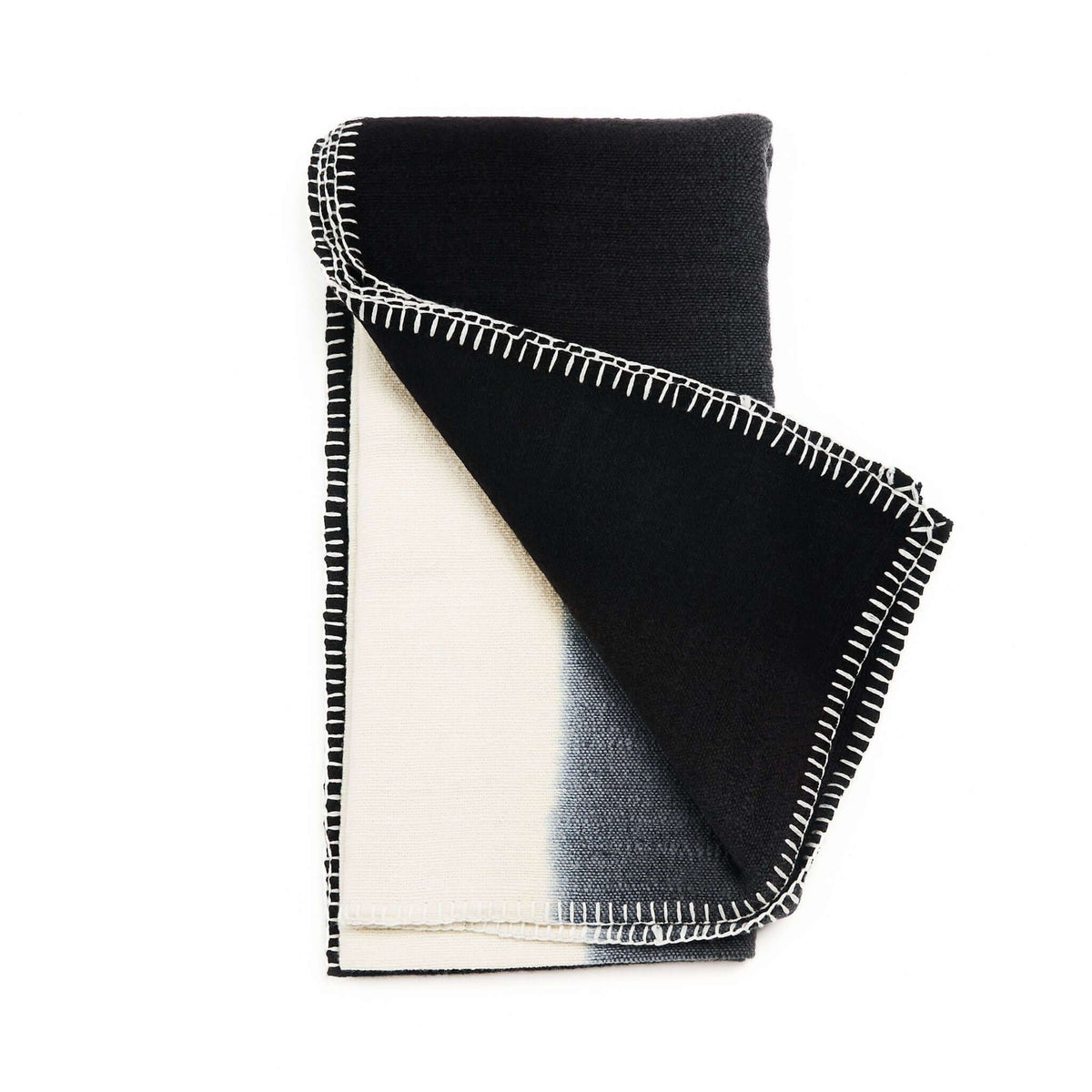 Variously Ink Black and White handwoven merino wool throw folded to reveal bold black-and-cream color blocking and contrasting white blanket stitching