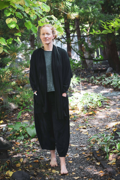 Woman wearing black merino wool lounge pants outdoors, showcasing a relaxed silhouette and natural wool comfort.