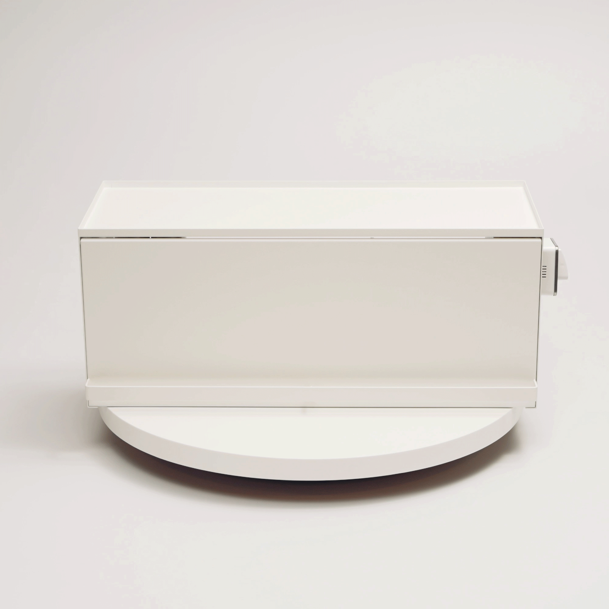 A hand demonstrates the white Yamazaki Home Open-Back Countertop Storage Rack - Steel on a round display platform, showing its open back, solid side panel and projecting front handle.