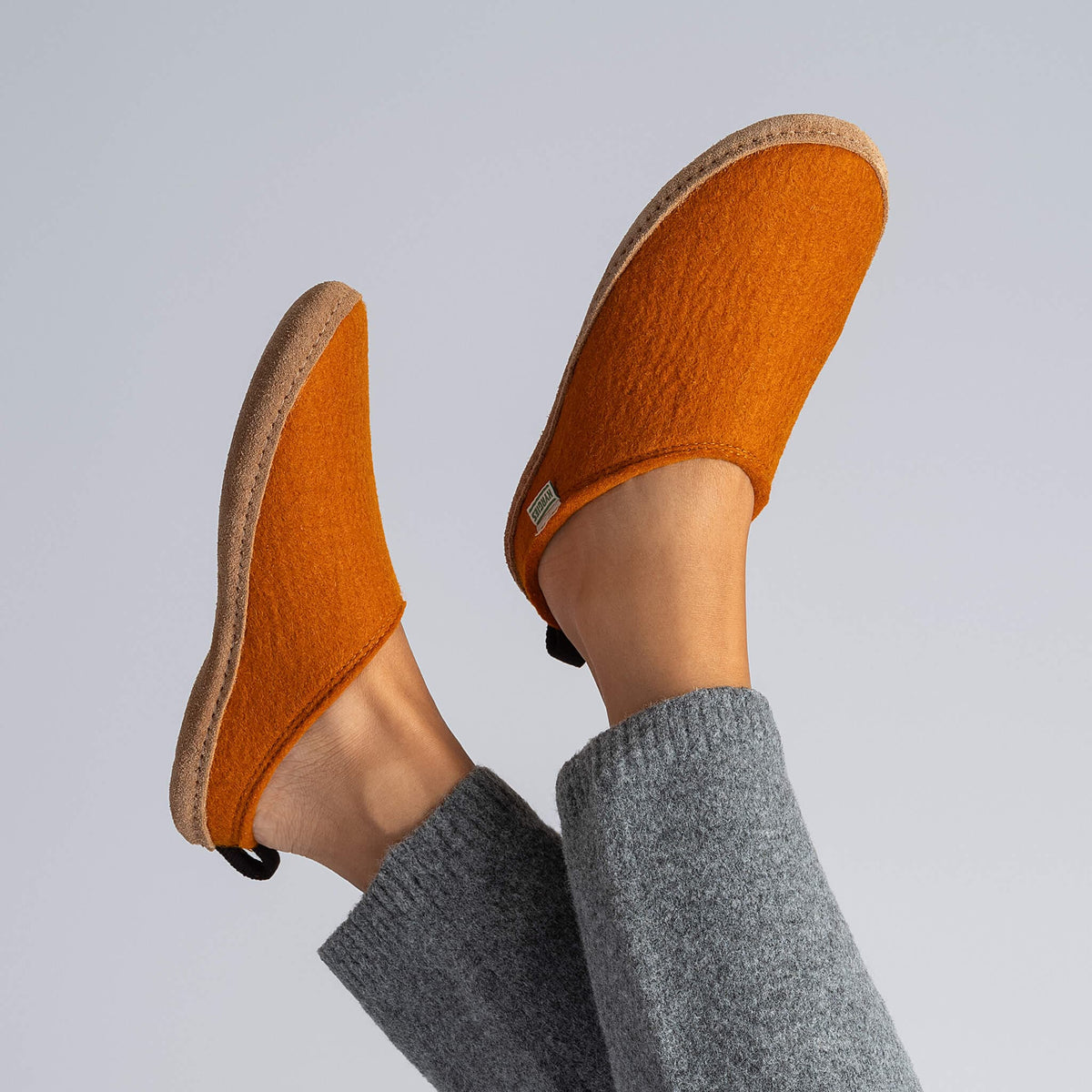 Kyrgies Indoor Wool Slides, rust wool felt, worn on feet in lifestyle setting