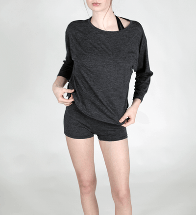 Woman wearing a charcoal merino wool lounge top featuring a relaxed silhouette, breathable comfort, and natural wool softness.